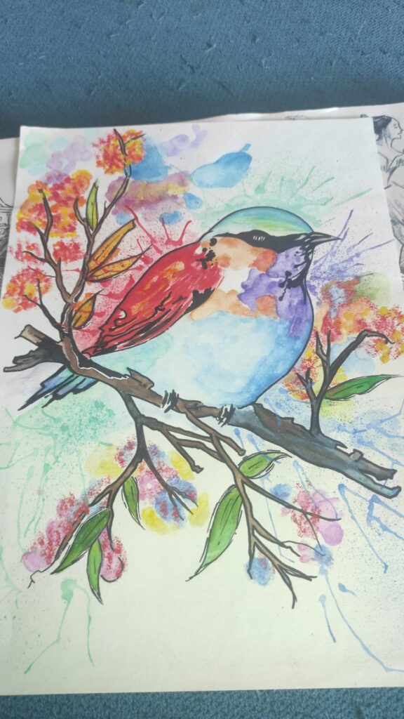 Dibujo de un pájaro posado sobre una rama con hojas. El ave presenta colores variados como azul, rojo, naranja y verde. El fondo está formado por manchas de acuarela en distintos colores, con salpicaduras que aportan un estilo artístico.