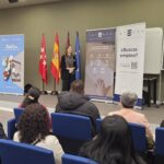 Jornada de "Cambia el rumbo" junto a la Agencia para el Empleo del Ayuntamiento de Madrid. Un persona realizando una presentación en una sala de conferencias ante un grupo de asistentes sentados en butacas azules. Detrás aparecen varias banderas institucionales (Comunidad de Madrid, España y Unión Europea) y dos roll-ups de Integra CEE con mensajes como “Contratamos talento, promovemos inclusión” y “¿Buscas empleo?”. A la izquierda, un cartel de la Agencia para el Empleo del Ayuntamiento de Madrid con el lema “Salta a tu agencia virtual de empleo”.