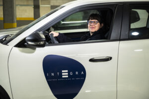 Profesional de Integra CEE posa en el interior de un vehículo corporativo identificado con el logotipo de la compañía. El coche se encuentra estacionado en el interior de un aparcamiento subterráneo.