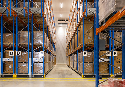 Almacén logístico con estanterías de gran capacidad Vista general del interior de un almacén logístico con pasillos amplios y estanterías metálicas de gran altura, con mercancía paletizada organizada por zonas.