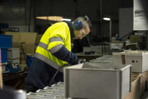 Servicio de manipulados de Integra CEE Profesional de Integra CEE realiza tareas de manipulado y ensamblaje de piezas en un entorno industrial, utilizando herramientas manuales y equipos de protección individual, junto a una línea de trabajo con componentes organizados