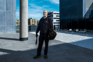 Trabajador de Integra CEE posa en la zona exterior de un edificio, equipado con herramientas de trabajo, como parte de un servicio de mantenimiento de instalaciones. 